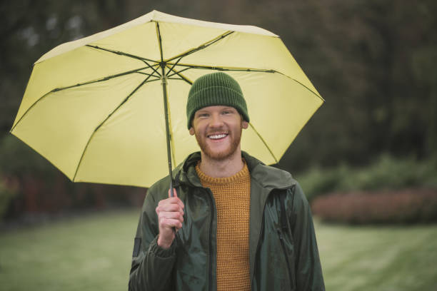 istock Young bearded man standing with yellow umbrella in hand 1285094772