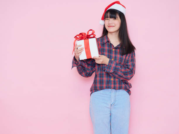 istock Smiling young woman wearing santa hat with holding gift box 1285095957