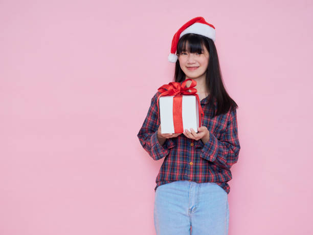 istock Smiling young woman wearing santa hat with holding gift box 1285095963