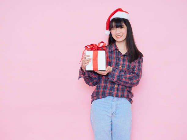 istock Smiling young woman wearing santa hat with holding gift box 1285095972