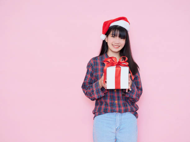 istock Smiling young woman wearing santa hat with holding gift box 1285095973