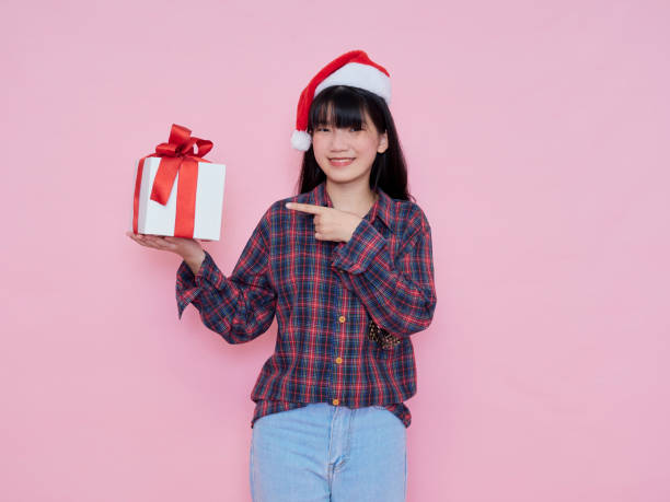 istock Smiling young woman wearing santa hat with holding gift box 1285095975