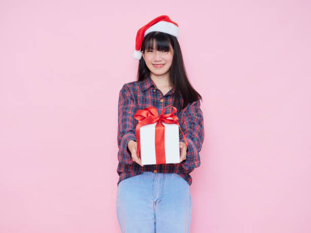 istock Cute girl giving white present box on pink background 1285095979
