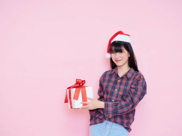 istock Smiling young woman wearing santa hat with holding gift box 1285095988