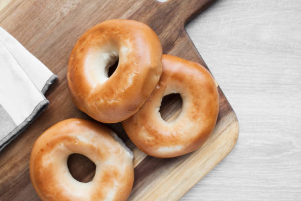 istock Plain bagels on a wooden board with a napkin viewed directly above 1285096109