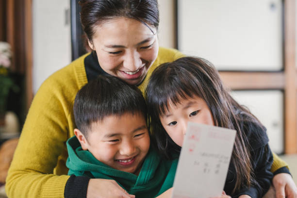 Japanese mother and children reading New Year's Card Japanese family reading Nengajyo, Japanese traditional New Year's Card together. japanese boy and girl stock pictures, royalty-free photos & images