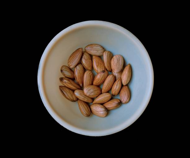 Collection Wet soaked almonds in a plastic bowl isolated on black.