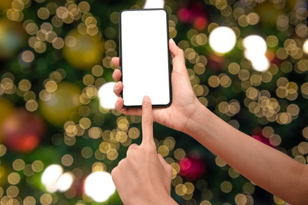 istock Close up hand holding phone isolated on white background with Illuminated  blurred bokeh of  Christmas tree decoration with  hanging lights ball. 1285098102