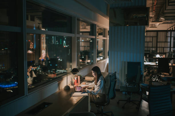 asiática chinesa trabalhador de colarinho branco mulher trabalhando tarde no escritório sozinho à noite correndo para relatório financeiro - fazer serão - fotografias e filmes do acervo