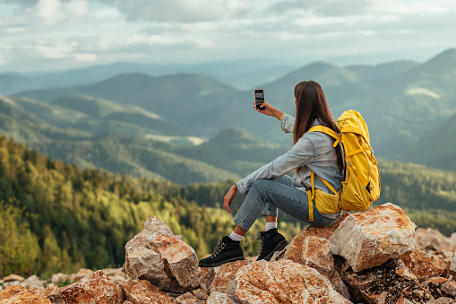 Young woman taking photos while hiking through the mountains