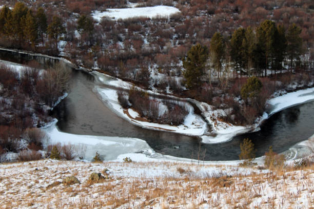 istock Breathtaking scenic freezing river high angle view from mountain peak. Winter stream with ice, snow and pine woodland and bush forest on riverbanks 1285102032