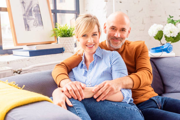 istock Happy couple relaxing on the sofa at home while looking at camera and smiling 1285102250