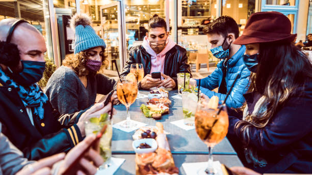 millennial people wearing face mask using smart phone outdoor - group of friends sharing content on socia media with cellphone - new normal and technology concept - apres ski winter friendship ski imagens e fotografias de stock