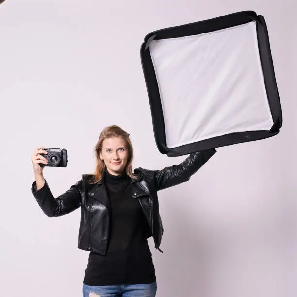 Girl Photographer. Softbox. Black clothes. White background.