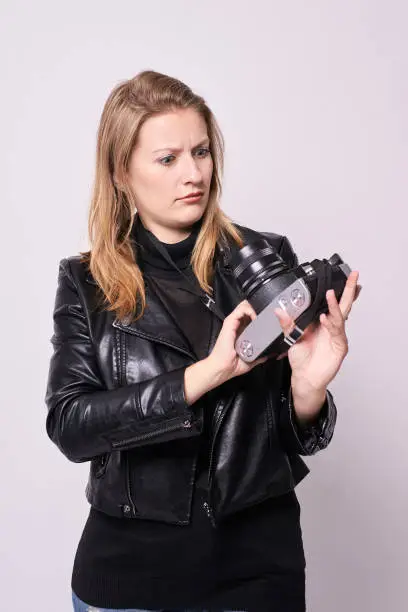 Girl with camera. Black clothes. White background.