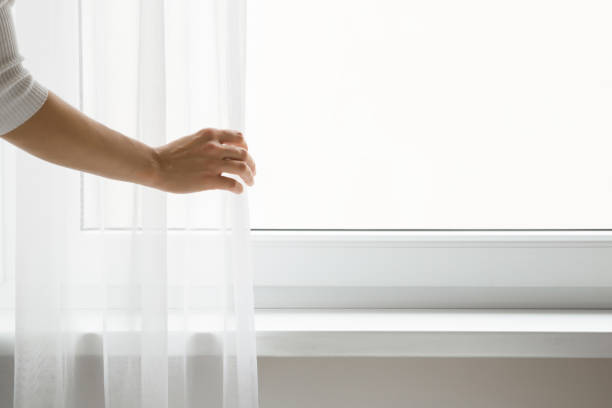 Young adult woman hand opening white day curtains at window. Closeup. Empty place for text on glass. Young adult woman hand opening white day curtains at window. Closeup. Empty place for text on glass. curtain rail stock pictures, royalty-free photos & images