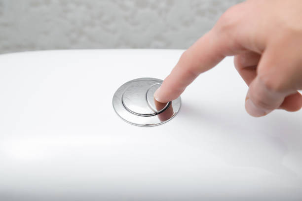 Young woman hand finger pushing button in toilet. Closeup. Young woman hand finger pushing button in toilet. Closeup. flushing toilet stock pictures, royalty-free photos & images