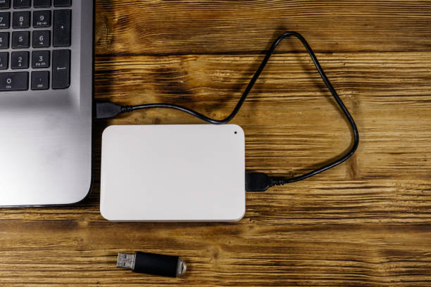 istock External HDD connected to laptop computer and USB flash drive on a wooden desk. Top view. Concept of data storage 1285106140
