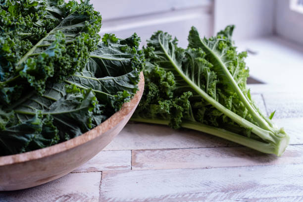 istock Kale leaves on wooden rustic background in the light window 1285106790