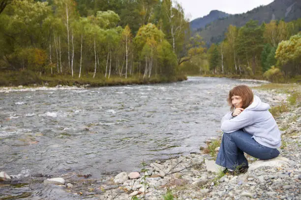 Smiling woman around Altai mountain river. Autumn.