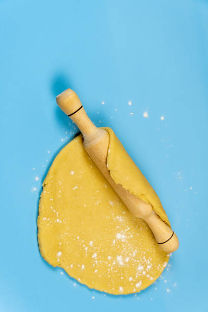 istock Thin sheet of fresh gingerbread dough with rolling pin on blue background. 1285106939