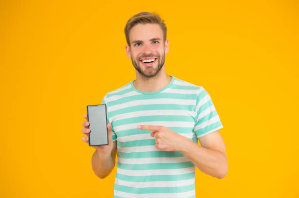istock Mobile services. Free internet. Application smartphone. Download and start play. Man pointing at smartphone. Pointing gesture. Index finger pointing. Pointing for advertising. Digital technology 1285107040
