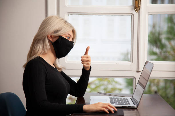 istock Young woman in mask having video call at home using laptop 1285108789