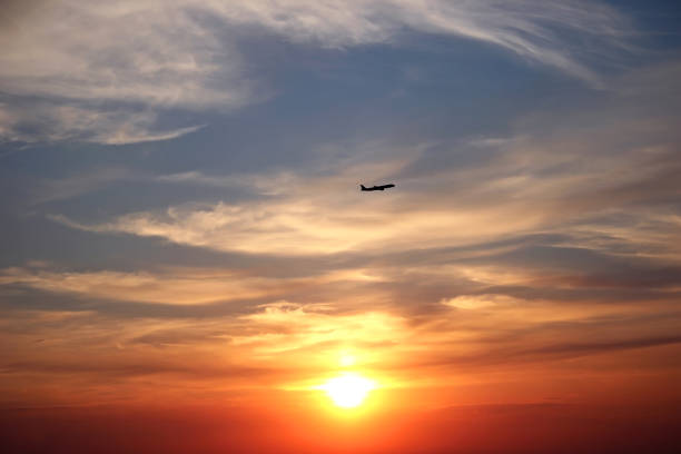 istock Beautiful sunset with clouds and a flying plane. 1285113471