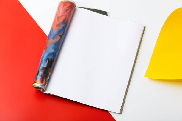 Open page magazine on red and white background, top view.