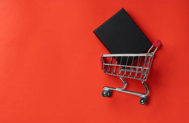 istock Shopping trolley with gift box on red background 1285114082