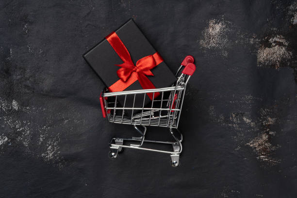 istock Shopping trolley with gift box and cope space on black background 1285114099
