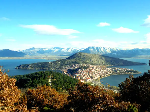 A view of the Greek town of Kastoria on a sunny day in autumn with snow-covered mountains in the background.