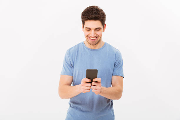 istock Attractive man with short dark hair chatting or typing text message using cell phone, isolated over white background 1285114810