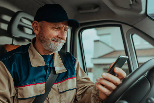 delivery man using his phone and checking orders - conductor oficio fotografías e imágenes de stock