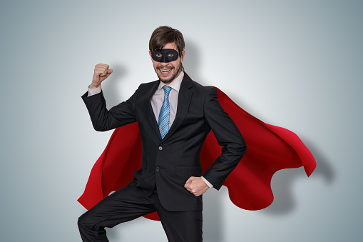 Profile view of aged 30-39 years old who is tall person with black hair caucasian male hero mid-air in front of white background wearing cape - garment who is excited and showing hand raised