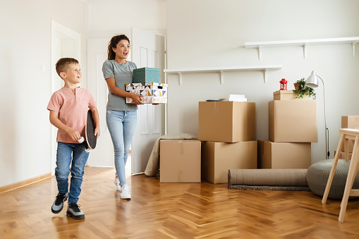 Happy Young Mother and Her Little Son Moving Boxes Into New Home Together Making a New Beginning