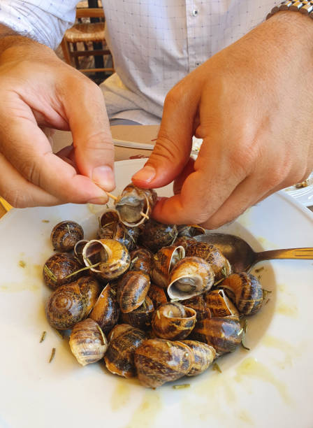 istock A man eats grape snails cooked in sauce with his hands in Greece 1285122801