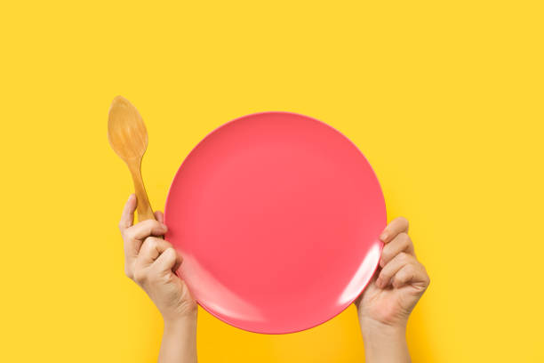 istock Woman holding a pink plate with both hands on a yellow background 1285123121