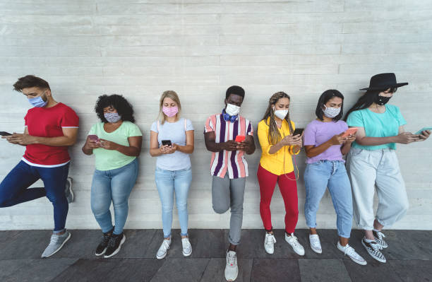 istock Young people wearing face mask using mobile smartphone outdoor - Multiracial friends having fun with new technology social media app during corona virus outbreak - Youth millennial lifestyle concept 1285126864