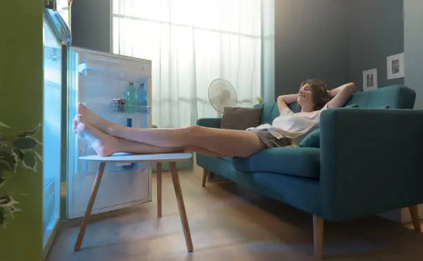 Photo of Woman cooling herself in front of the open fridge