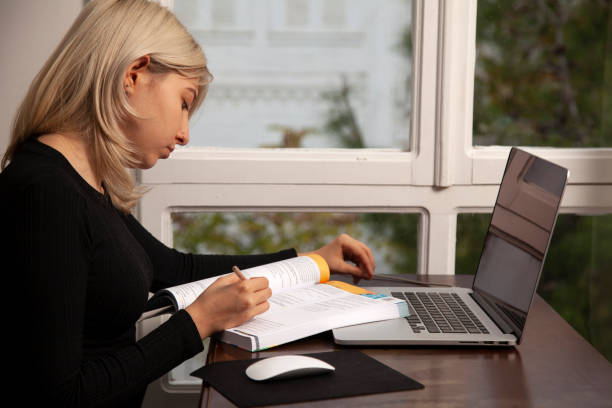 istock Young woman working on laptop and with test books 1285126931