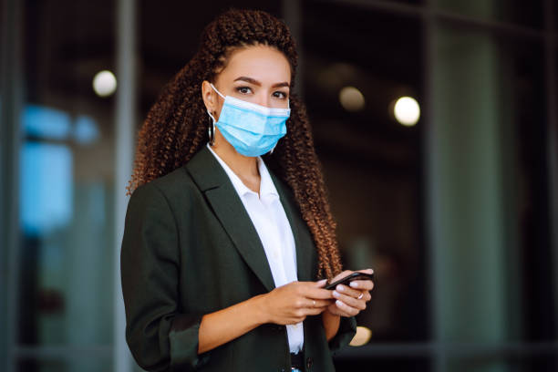 istock Portrait of a business woman wearing a protective mask with phone solves work issues. 1285127130
