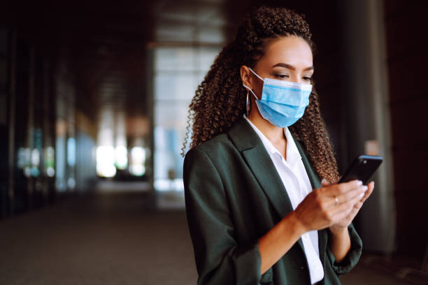 istock Portrait of a business woman wearing a protective mask with phone solves work issues. 1285127145