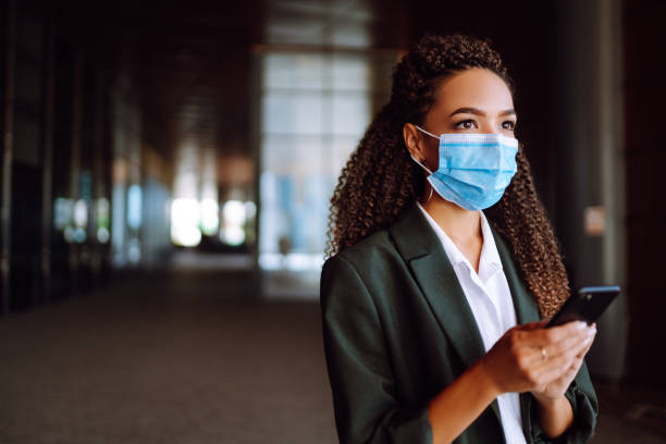 istock Portrait of a business woman wearing a protective mask with phone solves work issues. 1285127175