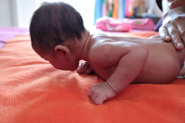 Photo of head holding exercise posture of a infant baby during tummy time.view from left.