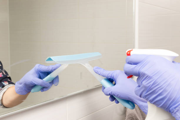 istock female hands sprinkle cleaning agent on the bathroom mirror and wipe it 1285131845