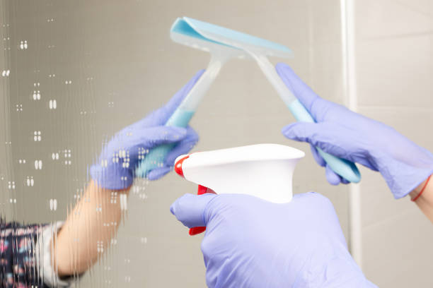 istock female hands sprinkle cleaning agent on the bathroom mirror and wipe it 1285131866