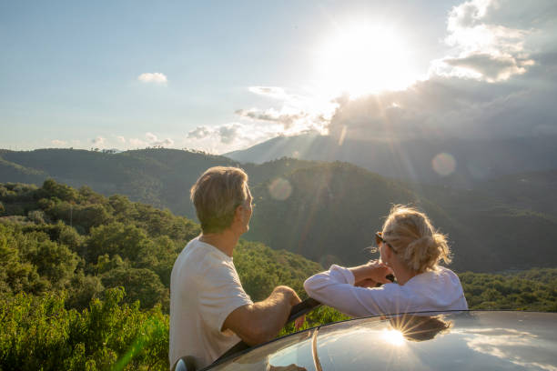 couples matures se détendre contre la voiture au lever du soleil - car door flash photos et images de collection