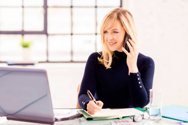 istock Confident businesswoman using phone and laptop while working online 1285137631
