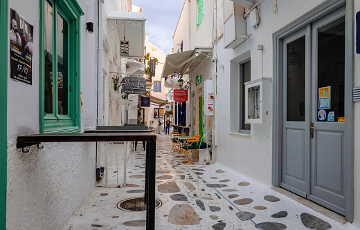 Tinos / Greece - October 17 2020: Whitewashed houses and cobblestone alley in Chora of Tinos, a Greek island situated in the Aegean Sea.